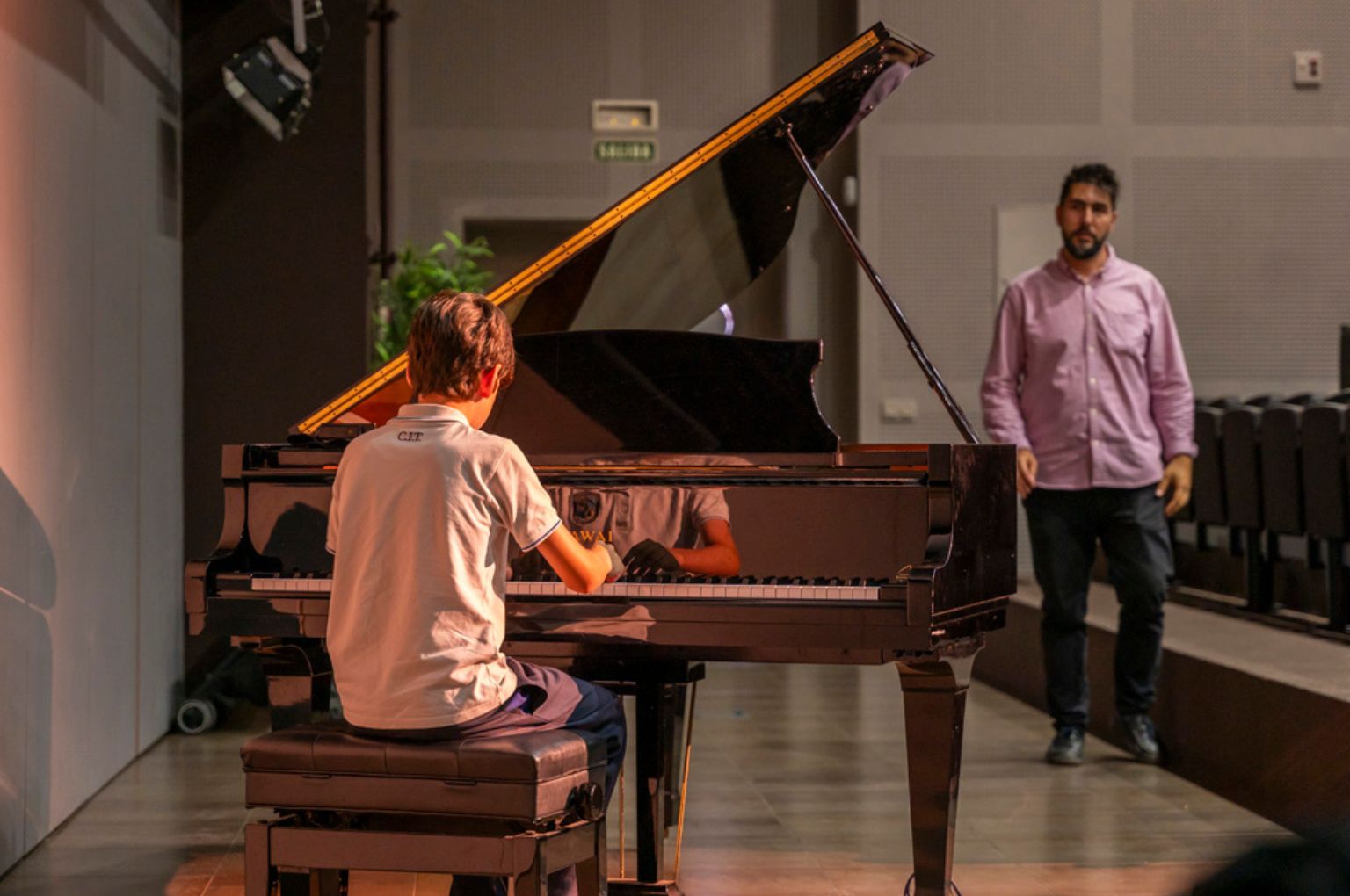 A student playing the grand piano in the music room at Colegio Internacional Torrequebrada